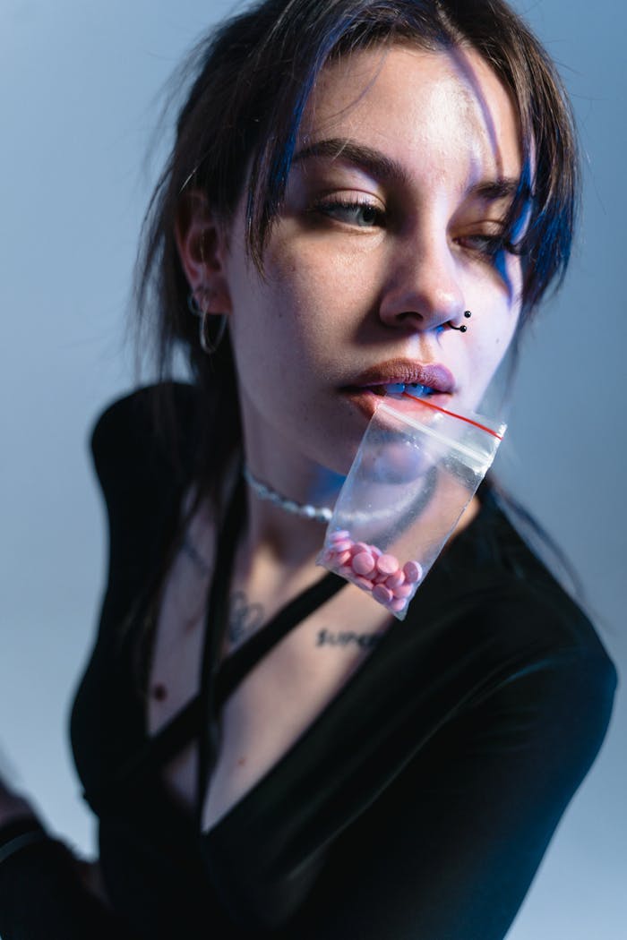 Young woman with pills in ziplock bag in conceptual portrait exploring themes of addiction.